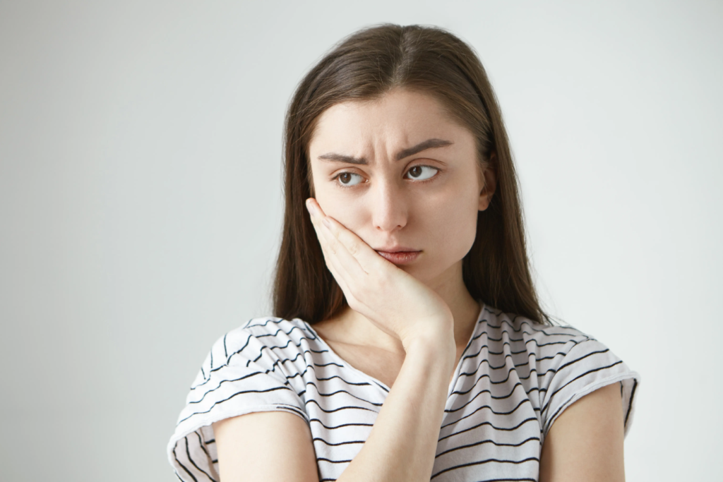 beautiful-unhappy-student-girl-dressed-striped-t-shirt-frowning-keeping-hand-her-cheek-while-suffering-from-toothache-feeling-miserable-helpless-because-terrible-unbearable-pain