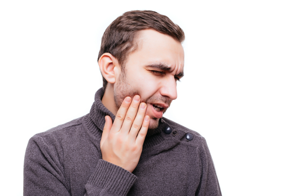 handsome-young-man-suffering-from-toothache-touching-his-cheek-stop-pain-against-white-wall
