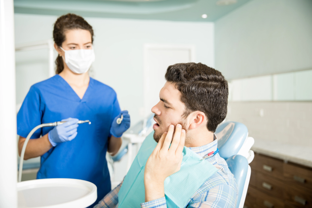 mid-adult-man-suffering-from-toothache-while-looking-dentist-with-tools-clinic
